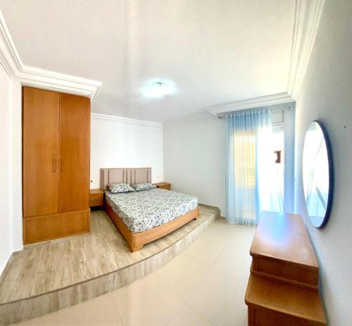 a bedroom with a bed and a wooden cabinet at Duplex El mansoura A1 in Kelibia