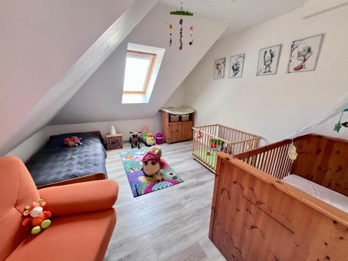 une chambre mansardée avec un lit et un berceau dans l'établissement Ruhige FeWo mit eingezäunten Garten - familienfreundlich, à Garz