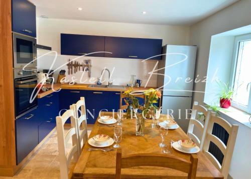 a kitchen with a wooden table and blue cabinets at La maison de Maïe Bail in Ploumagoar
