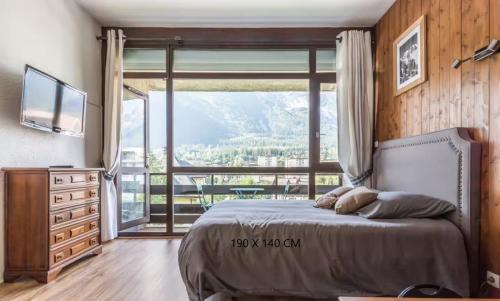 une chambre avec un lit et une grande fenêtre dans l'établissement Studio 25m2, Lumineux - Chamonix Centre - Vue MontBlanc, à Chamonix-Mont-Blanc