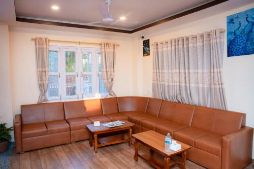 a living room with a brown leather couch at Hotel Samip in Pokhara