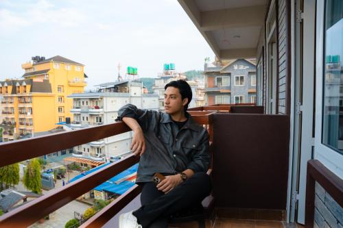 a man sitting on a balcony looking out of a window at Hotel Samip in Pokhara