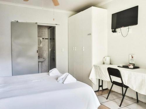 a bedroom with a bed and a table and a television at Nikita Portuguese Restaurant and Motel in Lanseria