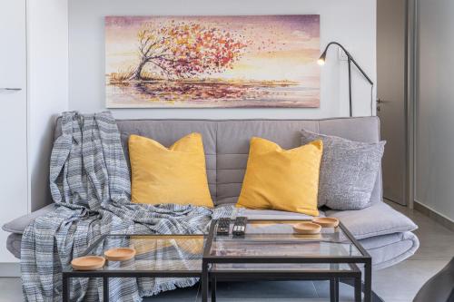a living room with a gray couch with yellow pillows at Foki Beach House in Fiskardho
