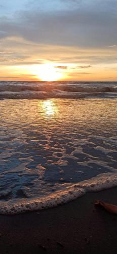 a sunset on the beach with the ocean at Bungalow Palmar del Viento by AMAUNA in Moñitos