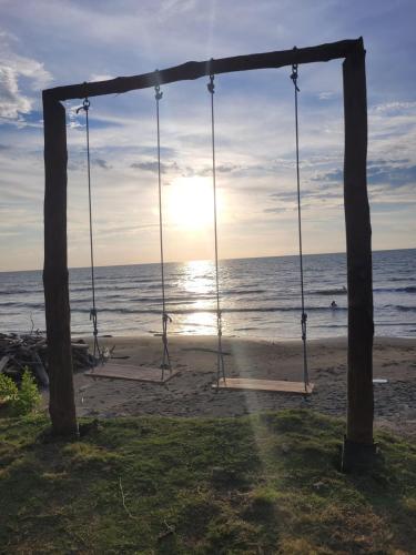 a swing on the beach with the sun setting at Bungalow Palmar del Viento by AMAUNA in Moñitos