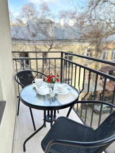 a table with two cups and flowers on a balcony at Apartments Black Sea in Odesa