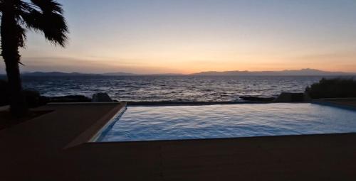 a swimming pool with a view of the ocean at sunset at Villa Joy in Nea Makri