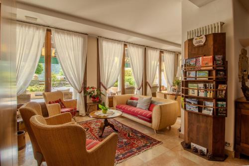 a living room with a couch and chairs and windows at Paradise Hotel & Wellness in Saint Vincent