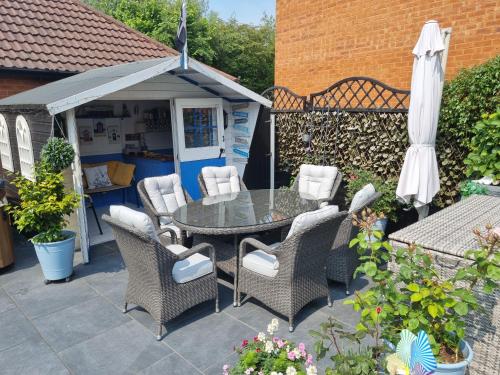 a patio with a table and chairs and an umbrella at Dungarvon House B&B, Luxury, Garden Hot Tub, Private Summerhouse, EV Point , 3x Bedroom Options in Weston-super-Mare