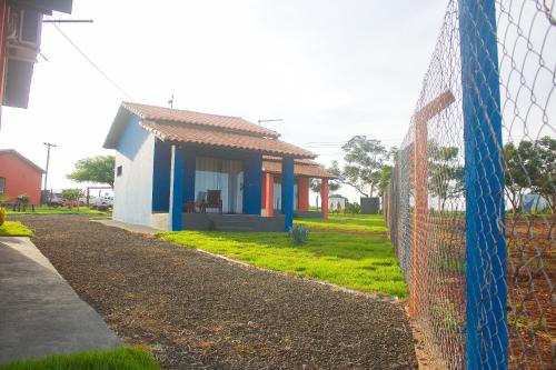 a small blue and white house behind a fence at Pousada Pôr do Sol in São João Batista do Glória