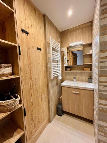 une salle de bain avec des murs en bois, un lavabo et un miroir dans l'établissement Les Vernettes, 6 people, garage, Wi-Fi, à Les Deux Alpes