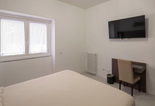 a white bedroom with a bed and a tv on the wall at Il Perugino Guest House in Rome