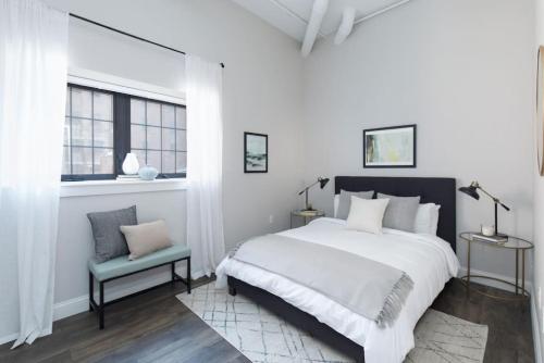 a white bedroom with a large bed and a chair at 200mbps speeds Laundry Long Stays in Boston