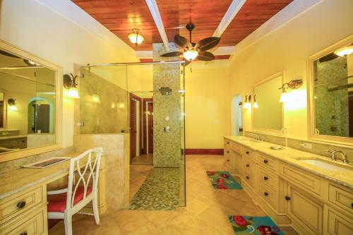 a bathroom with a shower and two sinks and a fan at Shoys Beach House - 5 bedroom villa on the Beach! in Christiansted