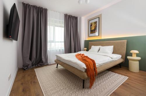 a bedroom with a bed with an orange blanket on it at Hubix Suites - City of Mara in Timişoara