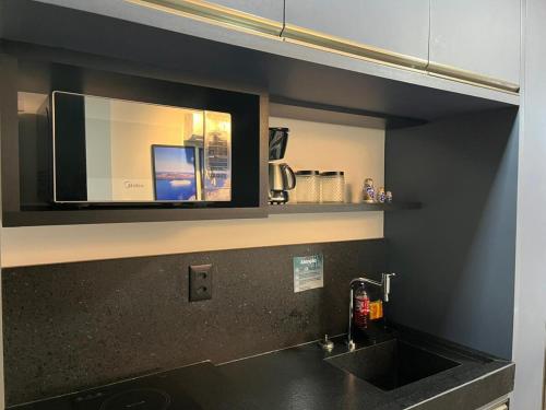 a kitchen with a sink and a microwave at Flat GRÉCIA na praia do Bessa, João Pessoa, Paraíba in João Pessoa