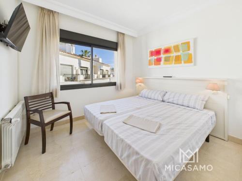 a white bedroom with a bed and a chair at Two-Bedroom Townhouse in Roda Golf in Roda