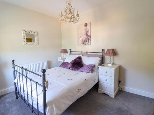 a bedroom with a bed with purple pillows and a chandelier at Dola in Betws-y-coed