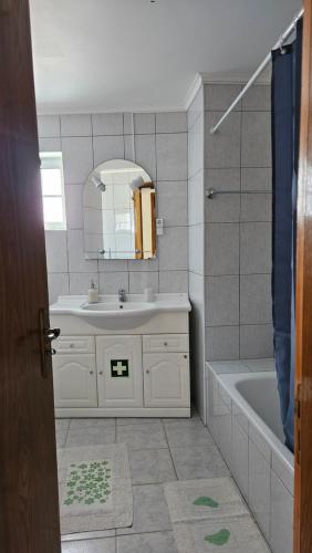 a bathroom with a sink and a tub and a mirror at Apartamento Terra e Mar II in Ponta Garça
