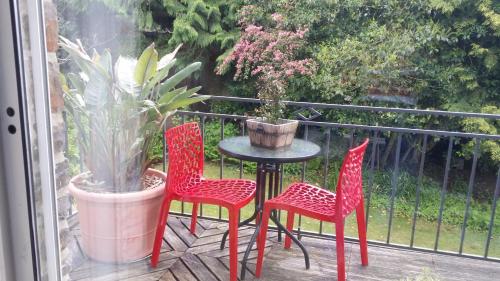 three red chairs and a table on a balcony at Hôtel de Tessé in Bagnoles de l'Orne