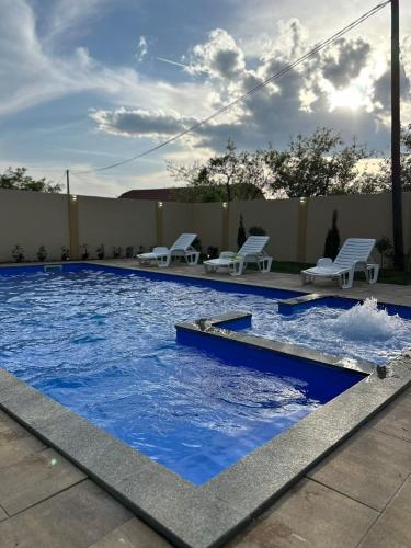 a swimming pool with blue water and white chairs at Villa Solis in Sarajevo