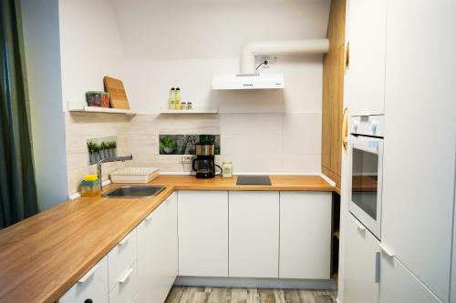 a kitchen with white cabinets and a wooden counter top at Mirandis Apartments - Modern Stays with Free Parking near Coresi Mall in Braşov