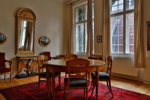 uma sala de jantar com mesa, cadeiras e janelas em Ferienwohnung Coco em Lübeck