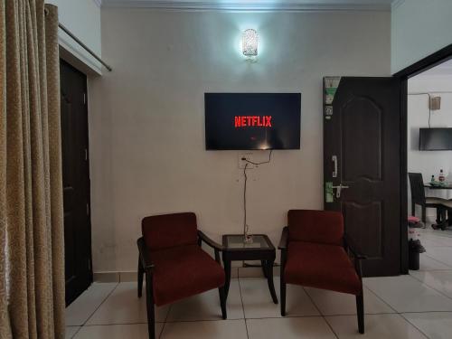 a waiting room with two chairs and a tv on the wall at Hillside Haven near Kainchi Dham in Bhowāli