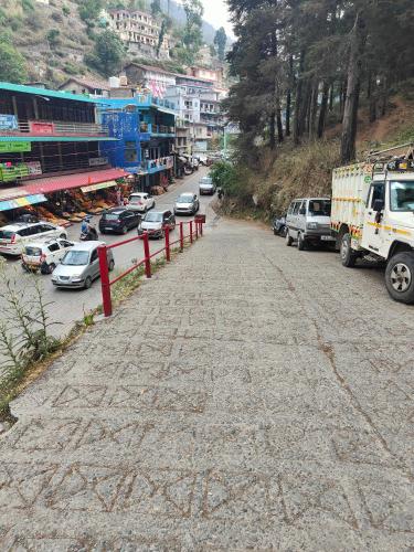 a street with cars parked on the side of a mountain at Hillside Haven near Kainchi Dham in Bhowāli