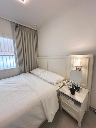 a bedroom with a white bed and a table with a night stand at Atelier PADO 101 in Busan