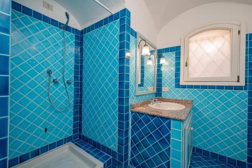a blue tiled bathroom with a shower and a sink at Ampio Appartamento 3 Min da Porto Cervo Centro in Liscia di Vacca