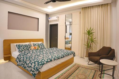 a bedroom with a bed and a chair at Mirpur Modern Spanish Villa - Elegant Comfort in the Heart of the City in New Mīrpur