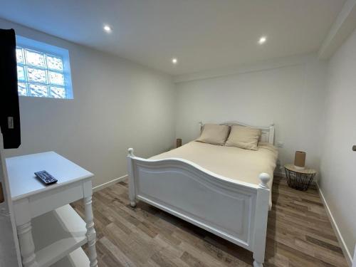 une chambre blanche avec un lit et un bureau dans l'établissement charmant appartement neuf en plein centre du village de collobrières, à La Celle-sous-Gouzon