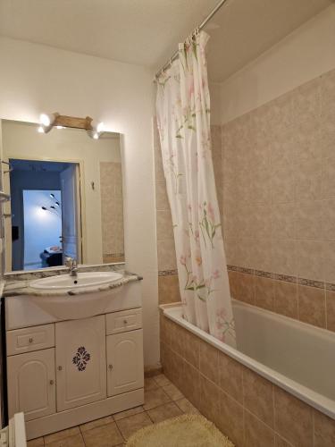 La salle de bains est pourvue d'un lavabo, d'une baignoire et d'un rideau de douche. dans l'établissement Fréjus appartement F2 avec place de parking, à Fréjus