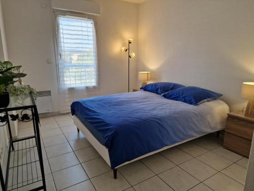 une chambre avec un lit avec des draps bleus et une fenêtre dans l'établissement Fréjus appartement F2 avec place de parking, à Fréjus