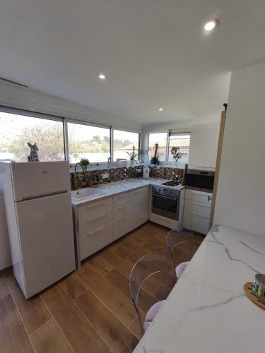 - une grande cuisine avec des appareils électroménagers blancs et des fenêtres dans l'établissement Charmant Studio Indépendant, à La Motte-dʼAigues