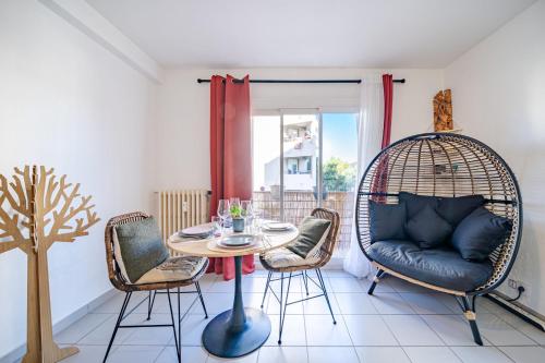 Cette chambre dispose d'une balançoire en rotin, d'une table et de chaises. dans l'établissement Appartement Rochat - Welkeys, à Antibes