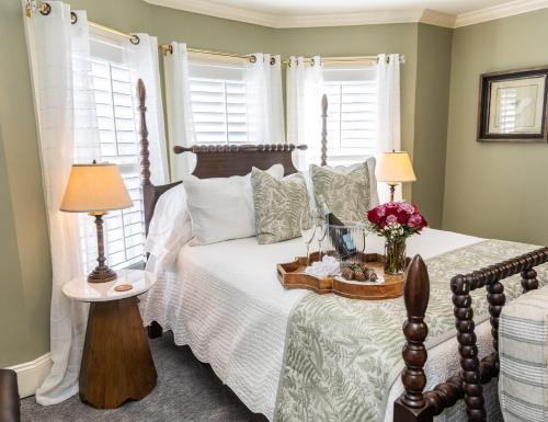 a bedroom with a bed and two windows at White Doe Inn Bed & Breakfast in Manteo
