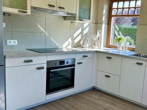 a kitchen with white cabinets and an oven at Au Coeur des Collines, Doucette in Ellezelles