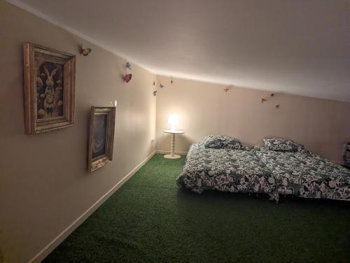 - une chambre avec un lit et un tapis vert dans l'établissement Spa familial De l'autre côté du miroir, à Mazingarbe
