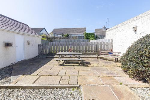 a patio with a picnic table and a fence at Coffee Cottage Portrush Holiday Home Self Catering in Portrush