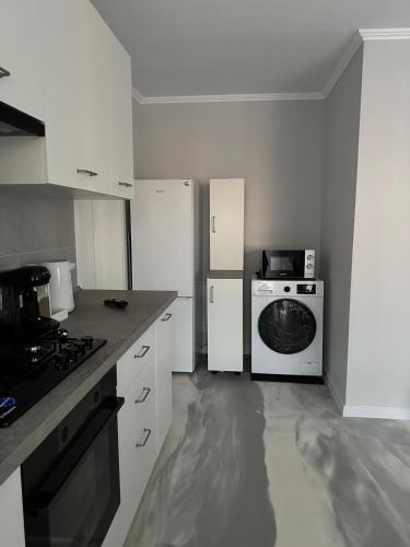 a kitchen with white cabinets and a stove and a dishwasher at Brillante Apartament in Floreşti