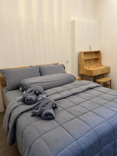 a bed with a blue blanket on top of it at Cozy townhome in Krabi town in Ban Khlong Chi Lat