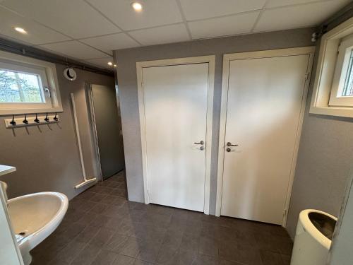 a bathroom with two white doors and a sink at Hyltena Stugby in Jönköping