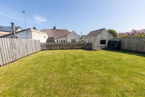 a backyard with a wooden fence and a yard at Coffee Cottage Portrush Holiday Home Self Catering in Portrush