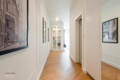 a hallway with white walls and wooden floors and paintings at Central Presov Bliss, right in the center with 1 free parking spot in Prešov