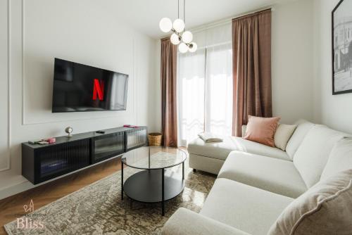 a living room with a white couch and a tv at Central Presov Bliss, right in the center with 1 free parking spot in Prešov