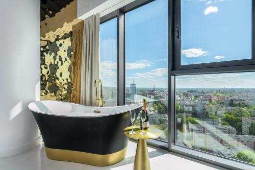 a bathroom with a tub in front of a window at Goldstar Apartament- Wanna z widokiem, 19 Piętro, Hanza Tower Szczecin in Szczecin