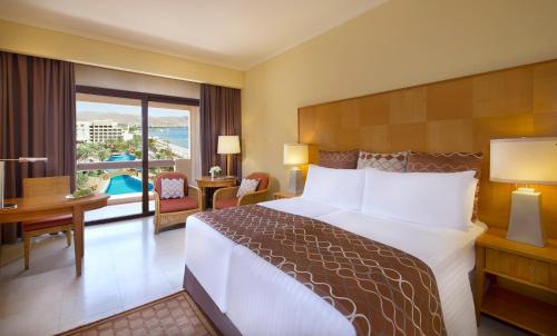 a hotel room with a large bed and a balcony at InterContinental Aqaba by IHG in Aqaba